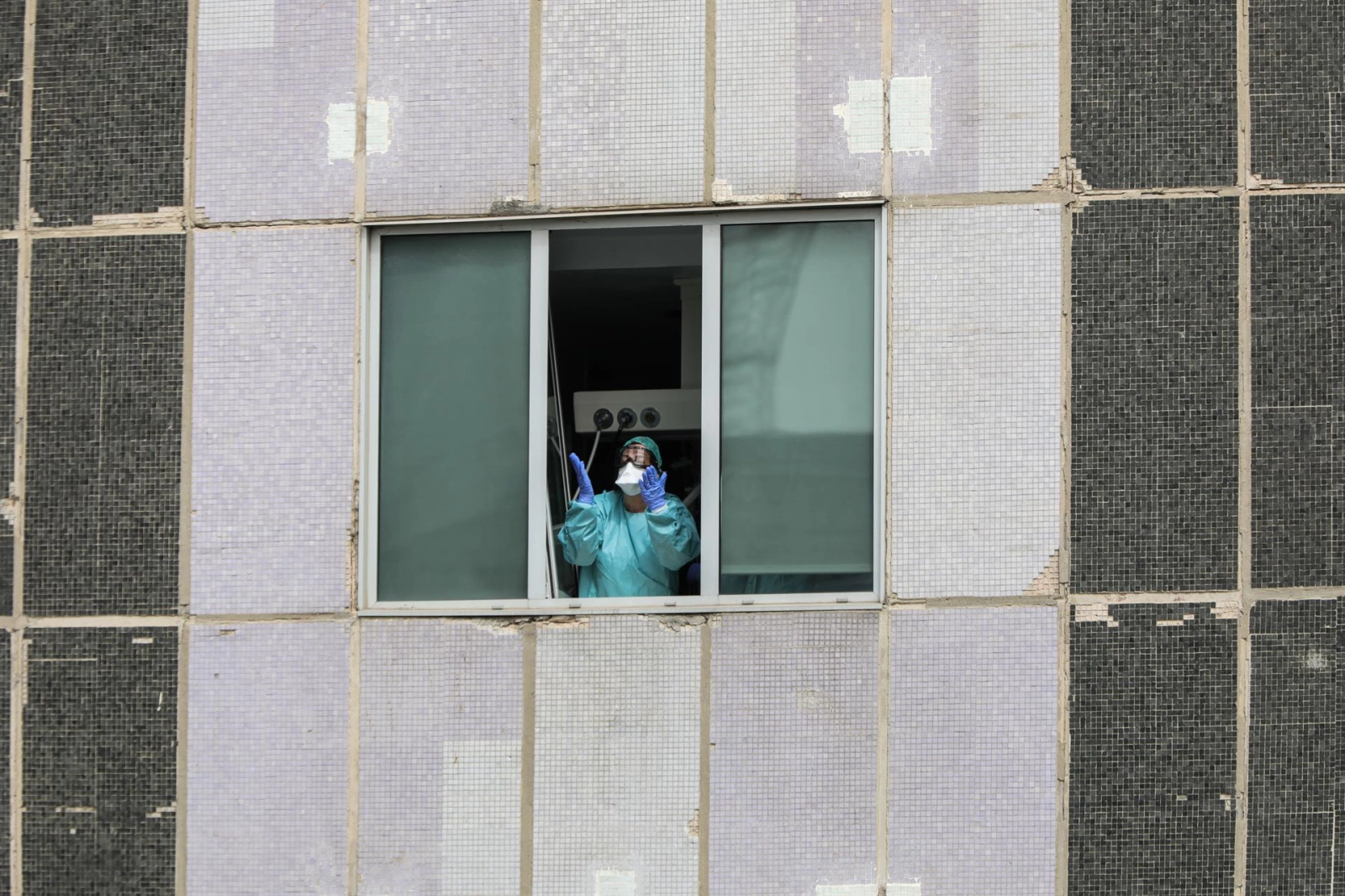 Una sanitaria del Hospital de La Paz totalmente protegida saluda y agradece el apoyo desde una de las ventanas del centro donde se lucha contra el coronavirus, en Madrid / Europa Press