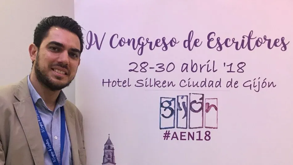 Juan maría de Comerón junto al cartel promocional del Congreso de Escritores Noveles