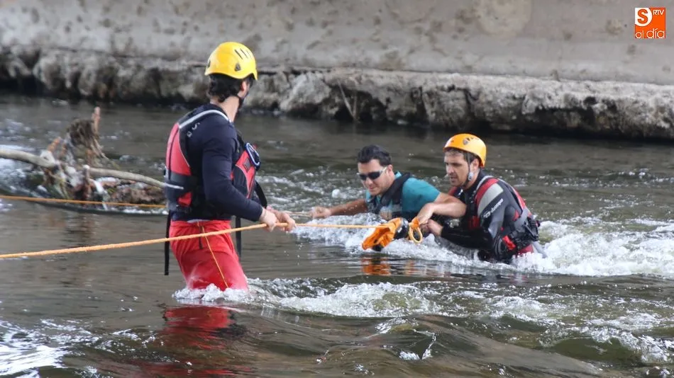 Dos bomberos auxiliando a uno de los pescadores que quedaron atrapados en el río