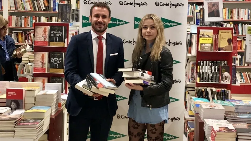 La ganador recibe los libros de manos de Adrián Rodríguez.
