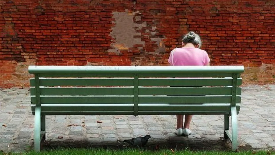 Una anciana espera sentada en un banco de madera. / EL NORTE