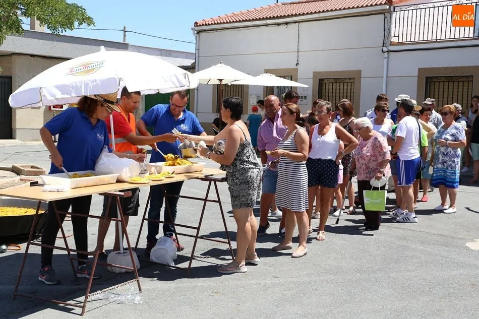 Los vecinos recogen sus platos de paella en la Plaza de España