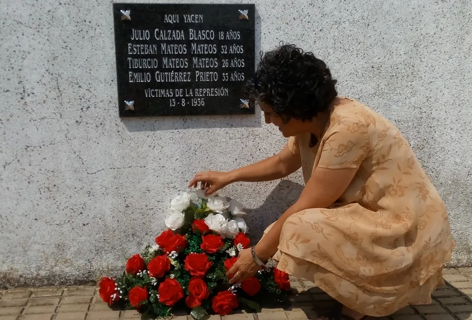 Isabel Mateos, en 2014, colocando un ramo de flores ante la placa con el nombre de las cuatro víctimas robledanas inhumadas en el cementerio de Boadilla
