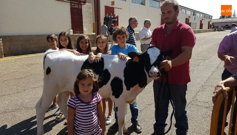 Un grupo de niños junto a una cría de la raza frisona