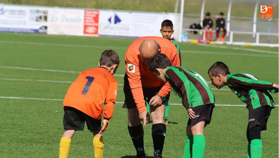 Un árbitro hace una indicación a dos futbolistas en un partido de base la temporada pasada.