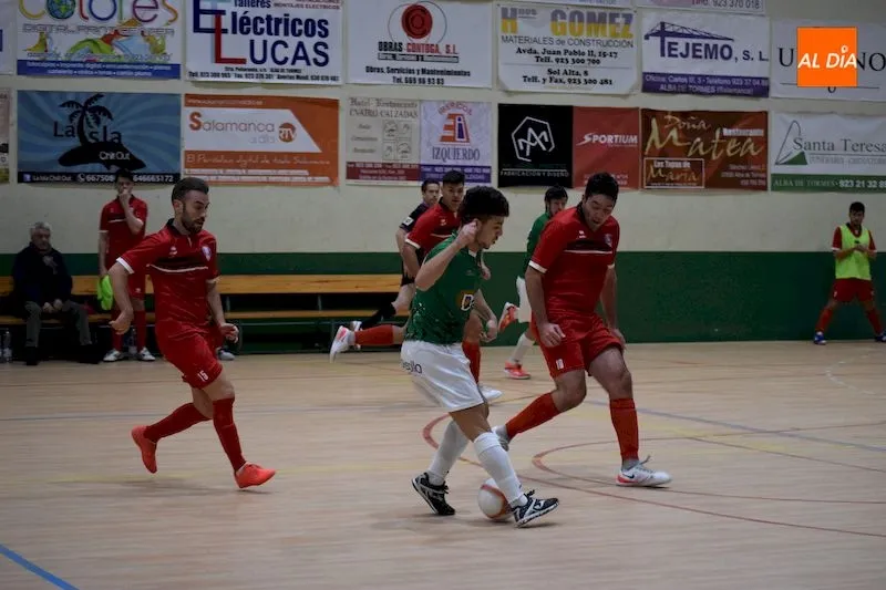 Juanan intenta dar un pase ante la presión de dos rivales