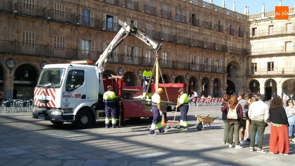 Operarios municipales retiran uno de los bancos de la Plaza Mayor
