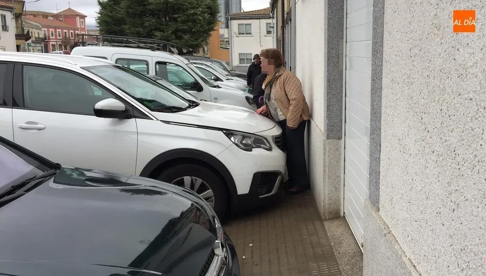 Una mujer intentando pasar por la acera, imposible hacerlo con el carrito de la compra