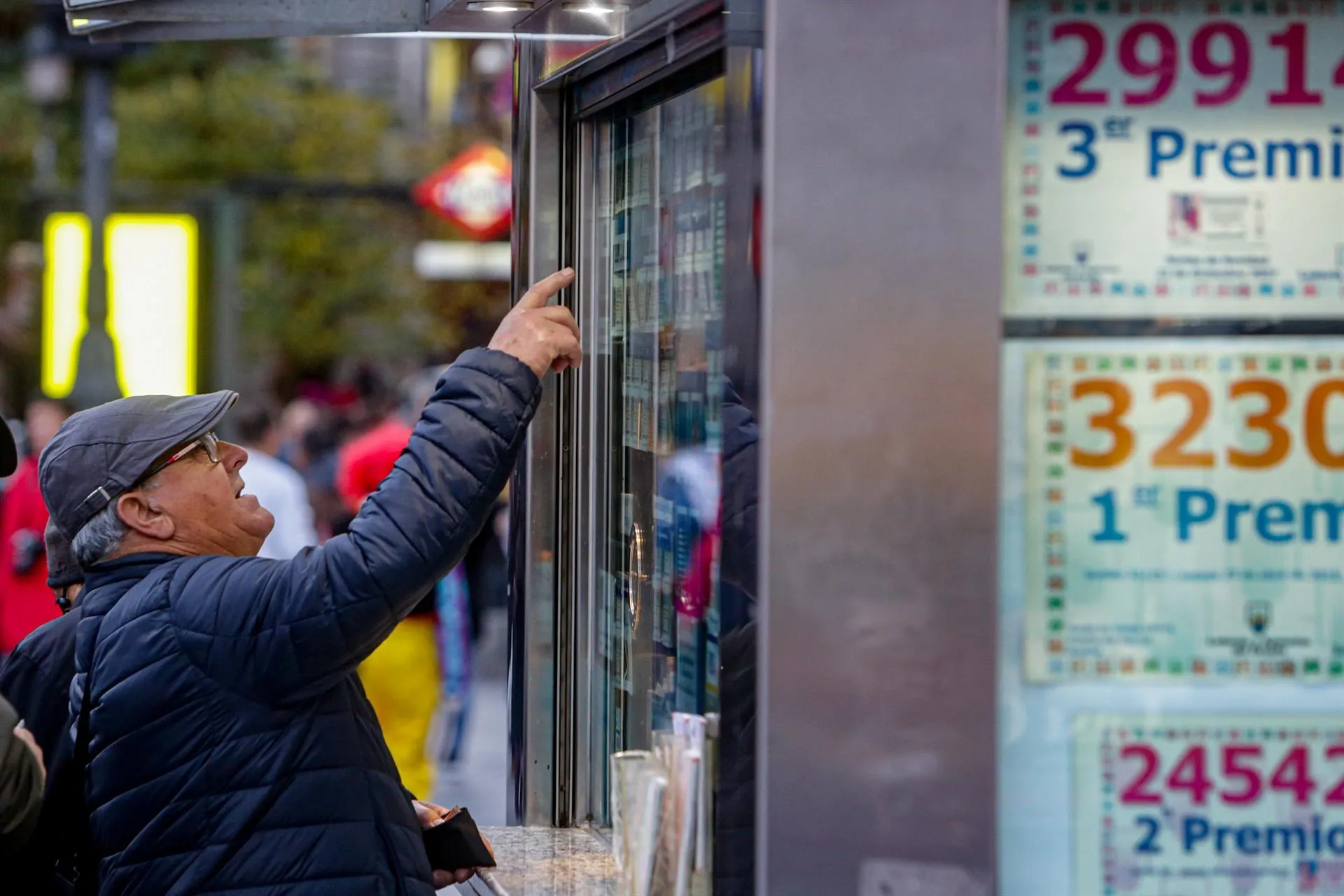 Un hombre señala el décimo de Lotería de Navidad que quiere comprar en una Administración en la plaza de Puerta del Sol / Europa Press
