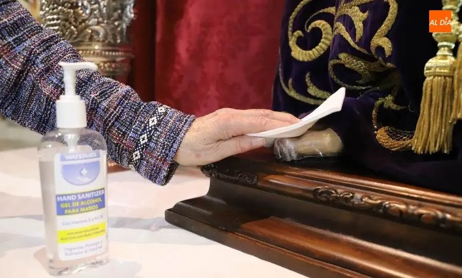 Voluntaria limpiando la talla, porque la había tocado uno de los fieles. Foto de Lydia González