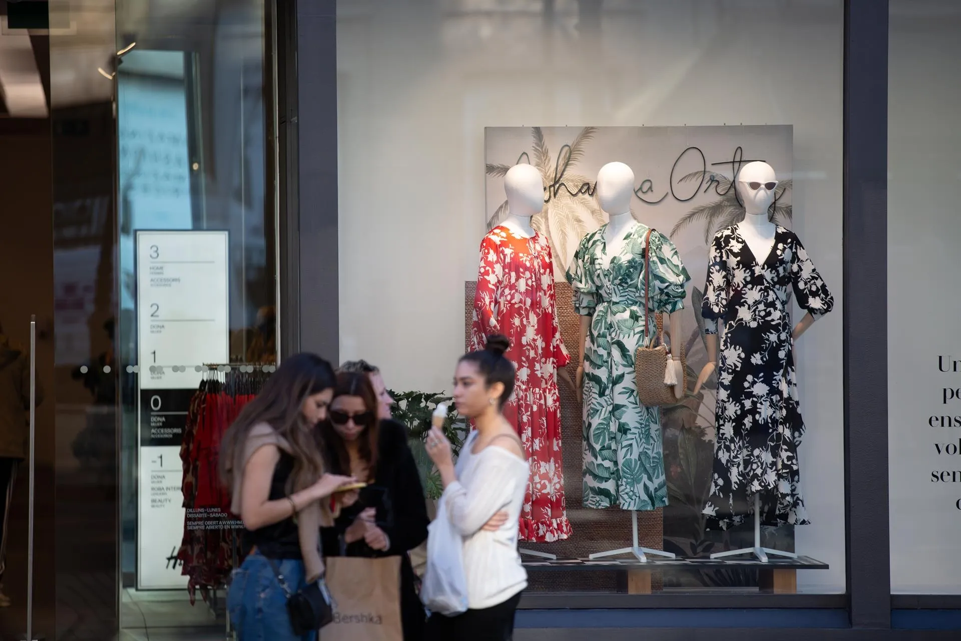 Unas jóvenes con bolsas de la marca Bershka y frente a un establecimiento de la misma cadena en Barcelona / Europa Press