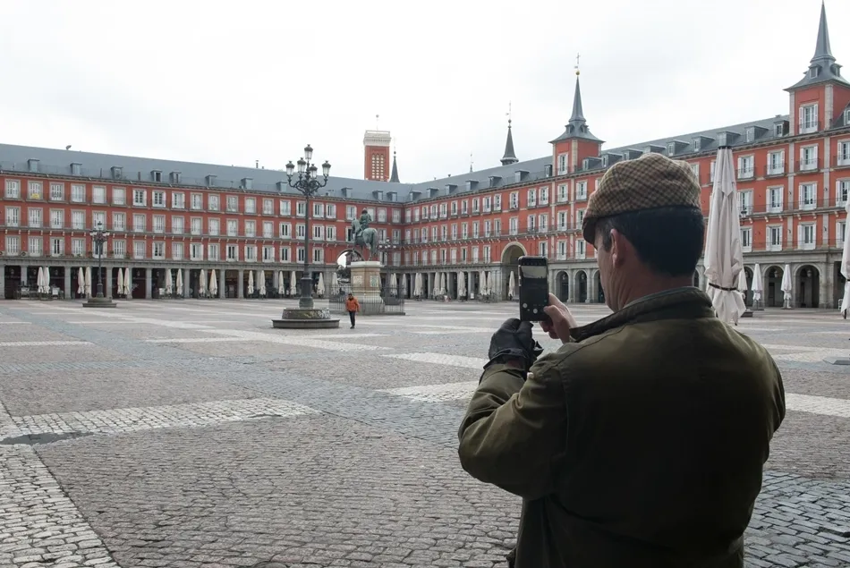 Un hombre hace una foto con su móvil a la céntrica Plaza Mayor de Madrid, vacía durante el estado de alarma. Foto EP
