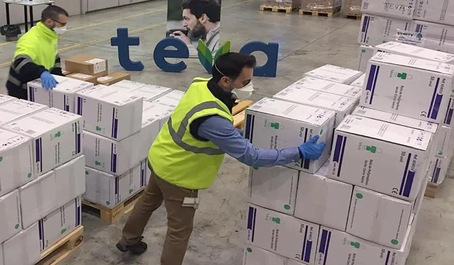 Dos trabajadores con mascarilla trabajan en el almacén de la compañía farmacéutica internacional TEVA. Foto EP