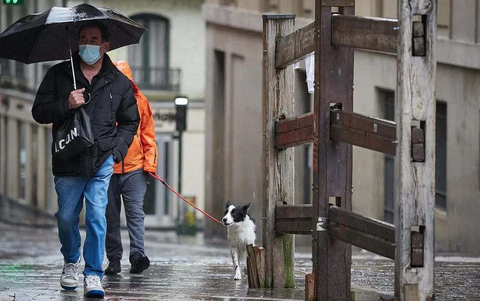 Un hombre con mascarilla camina bajo la lluvia - Eduardo Sanz - Europa Press