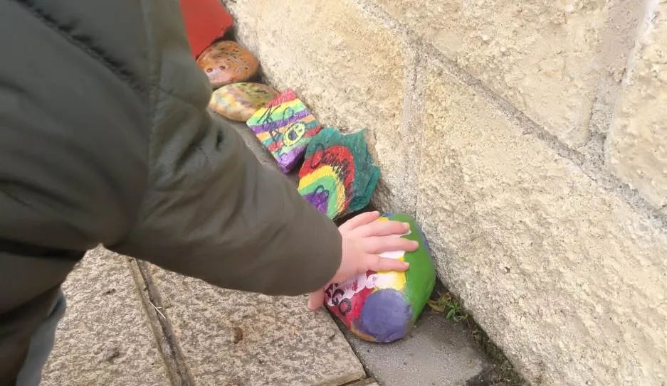Uno de los menores de Los Alcaldes coloca su piedra decorada para este Camino de Felicidad