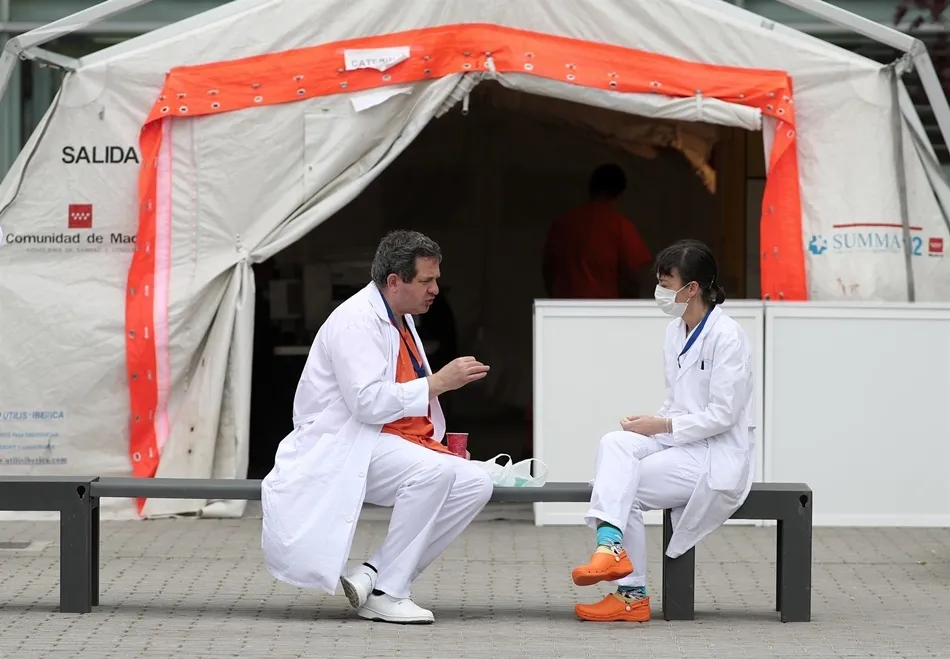 Dos sanitarios conversan sobre un banco a las afueras del hospital de campaña de IFEMA. Foto: EP