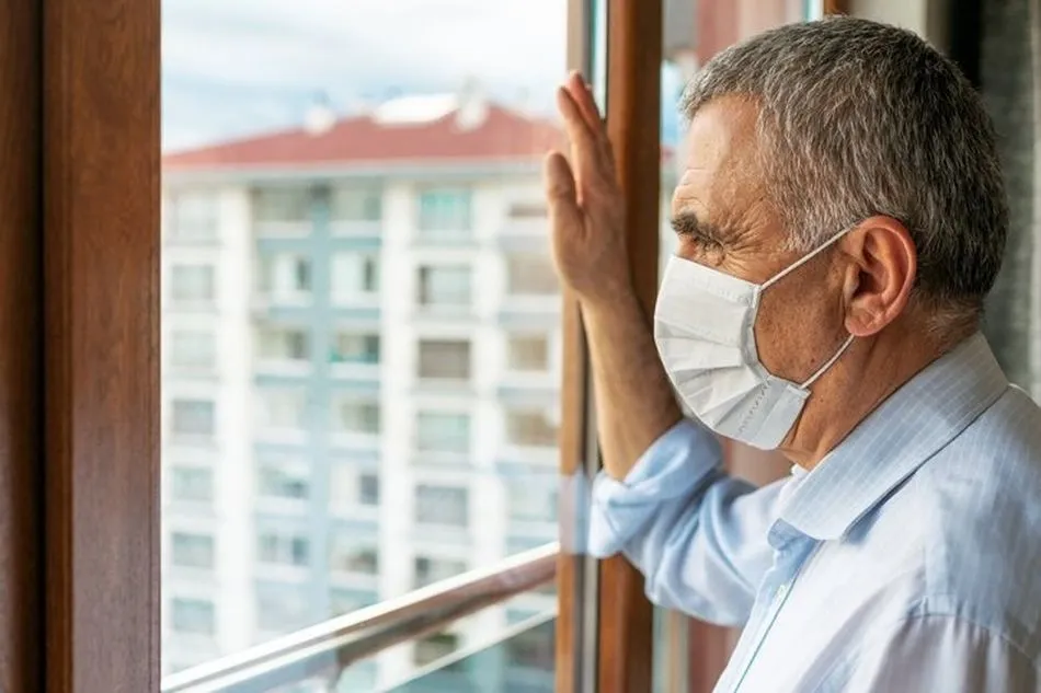 Un hombre con mascarilla observa a través de una ventana. Foto: EP