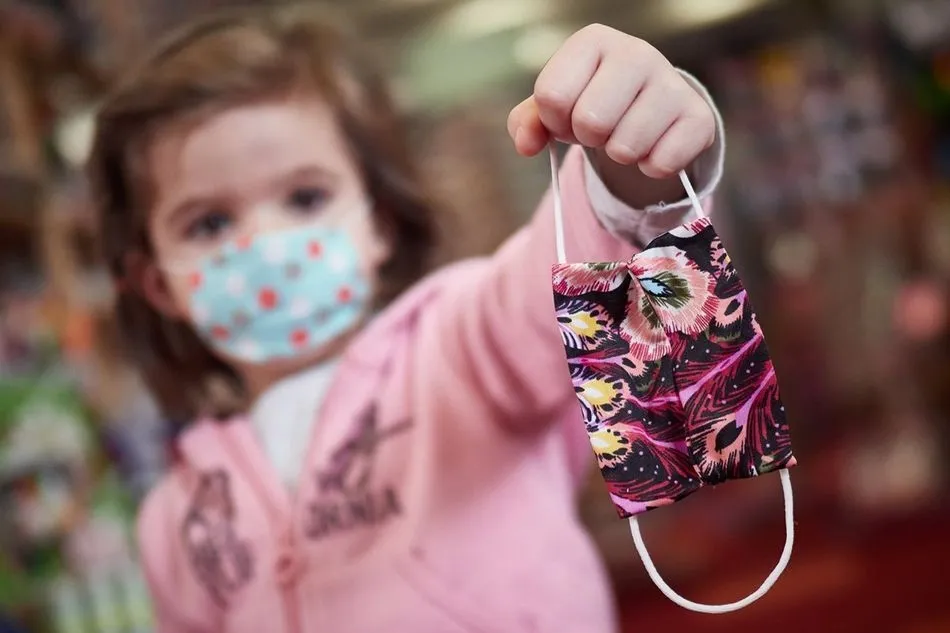 Una niña muestra una mascarilla
