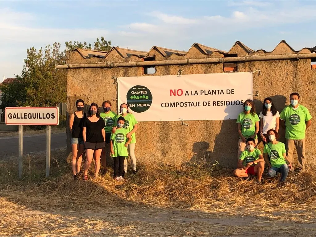 Integrantes de la plataforma Gajates sin mierda junto a una de las pancartas que han colgado