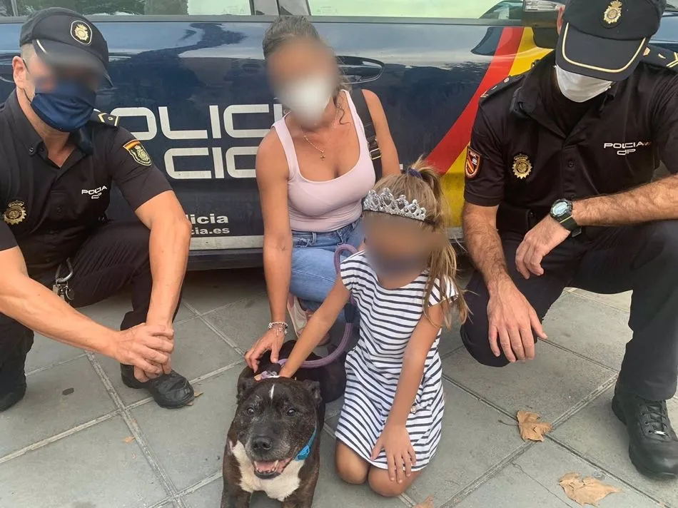 Agentes de la Policía Nacional con el perro y varios miembros de la familia