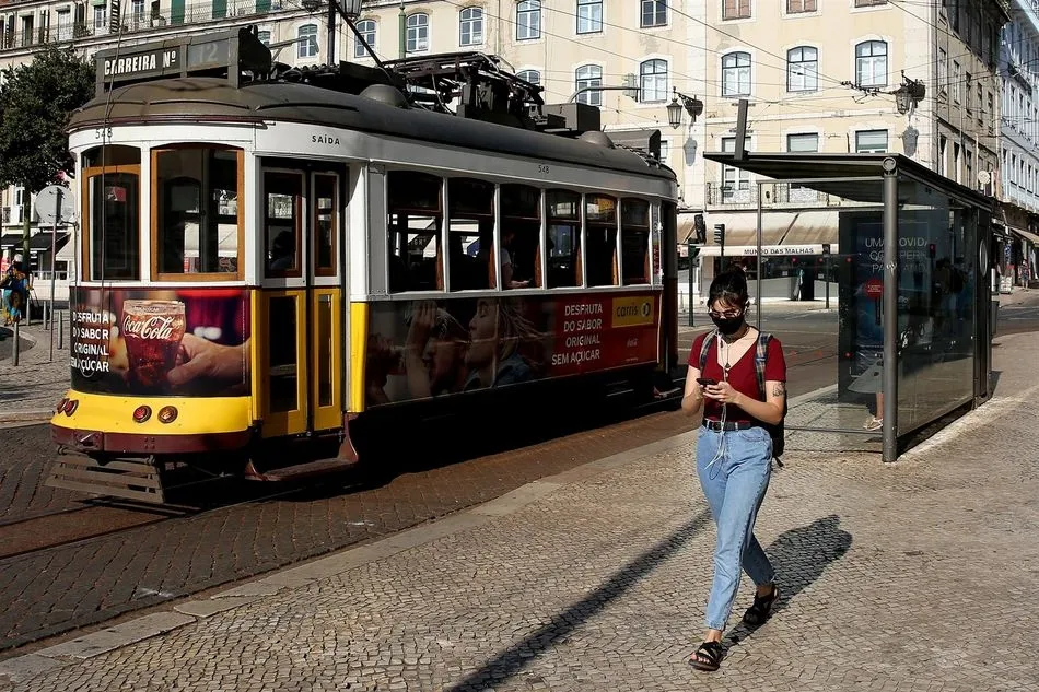 Una mujer con mascarilla junto a un tranvía en Lisboa. Foto: EP
