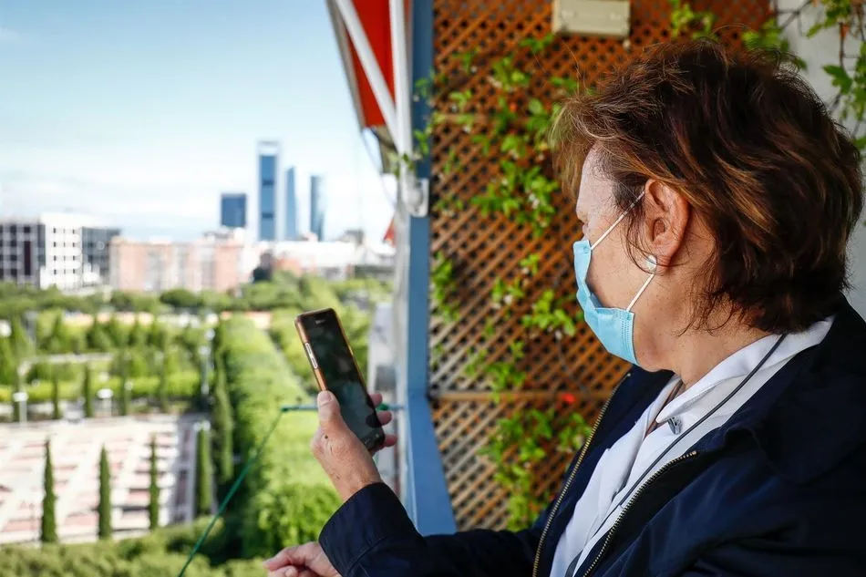 Araceli, usuaria de audífonos intracanales y miembro de FIAPAS, observa su teléfono móvil desde un balcón. Foto: EP