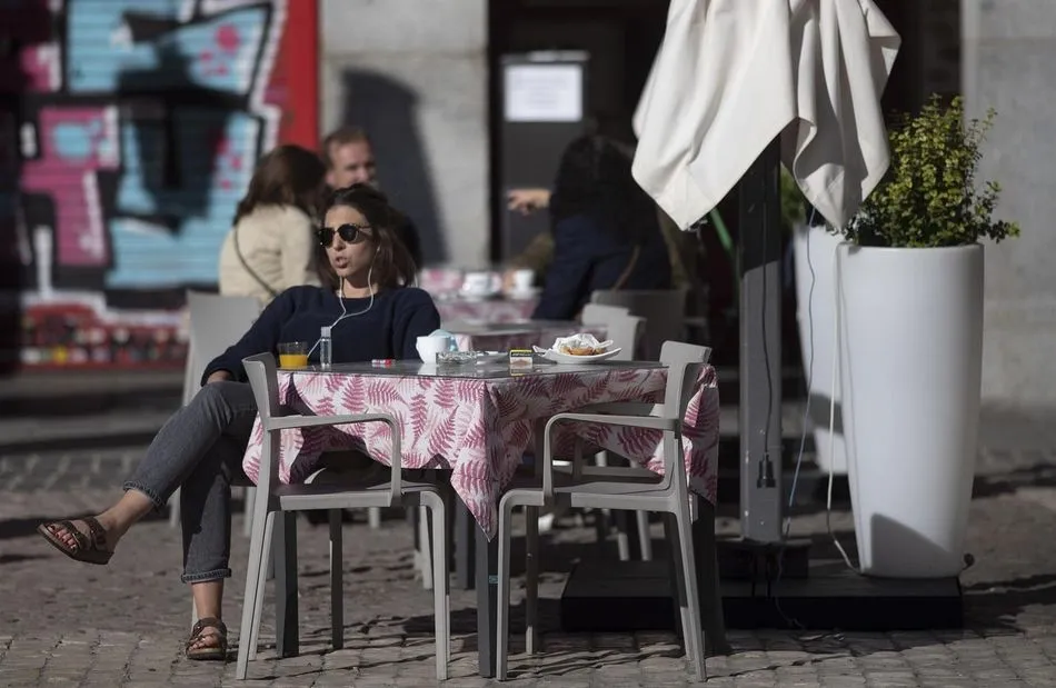 Una mujer disfruta en una terraza de la Plaza Mayor durante el primer día con nuevas restricciones en la movilidad. - Eduardo Parra - Europa Press
