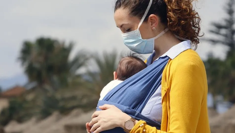 Una mujer protegida con una mascarilla da un paseo con su bebé. Foto Álex Zea - EP Archivo