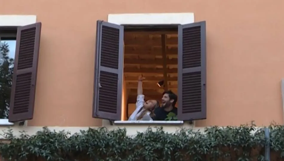 Una pareja se asoma a la ventana durante el confinamiento