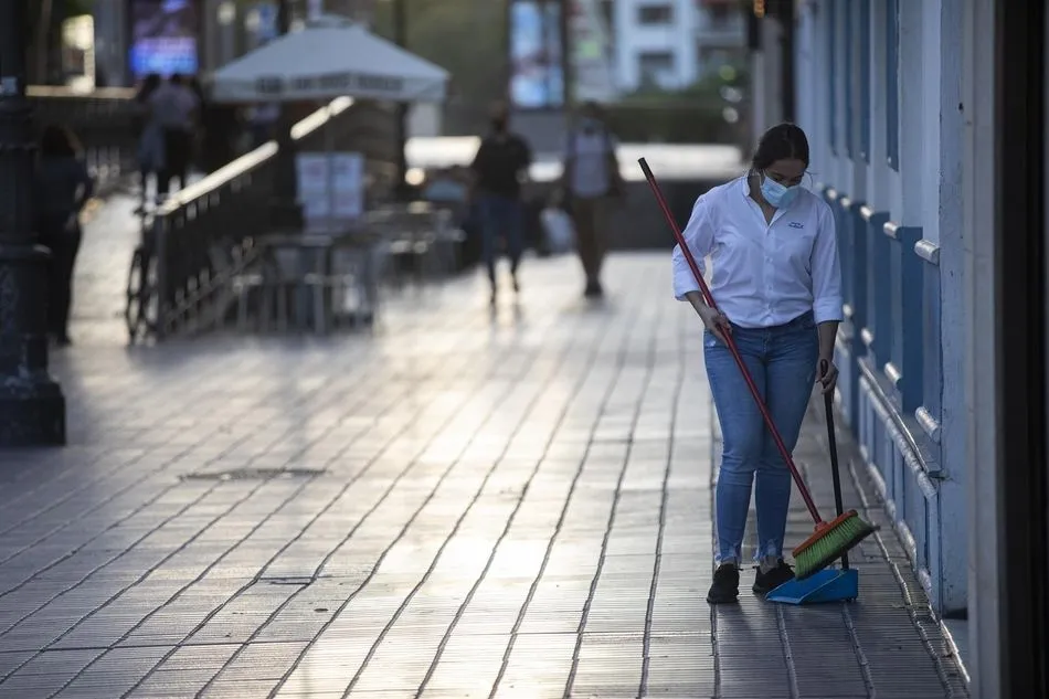 Una camarera tras recoger el mobiliario de la terraza de un bar
