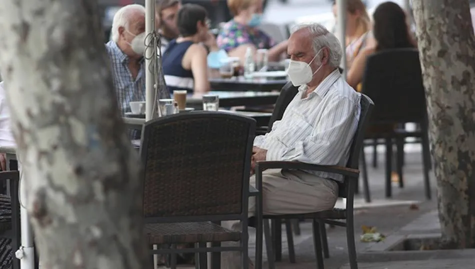 Un hombre con mascarilla sentado en una terraza