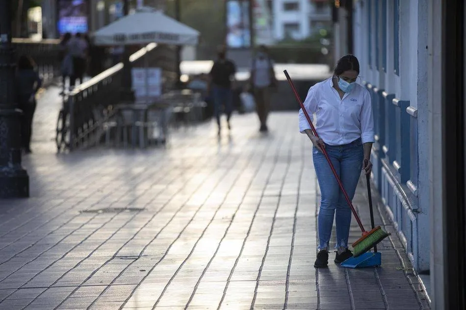 Una camarera tras recoger el mobiliario de la terraza de un bar