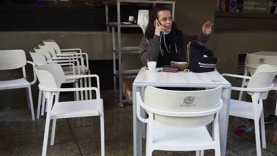Una joven habla por teléfono mientras toma un café en una terraza. Foto: EP