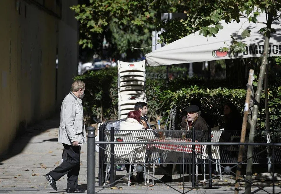 Un hombre camina frente a la terraza de un bar