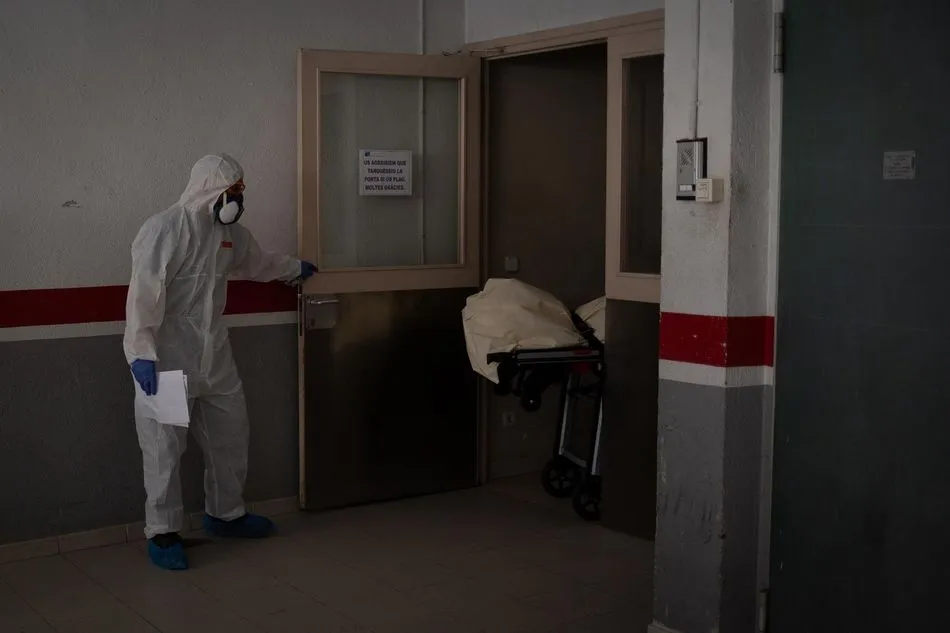 Varios operarios protegidos de los servicios funerarios trasladan el cuerpo de una persona fallecida en una residencia de ancianos de Girona durante la pandemia