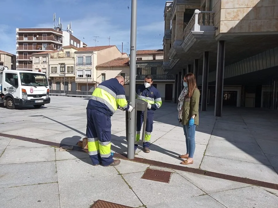 Operarios municipales instalando una papelera - Archivo