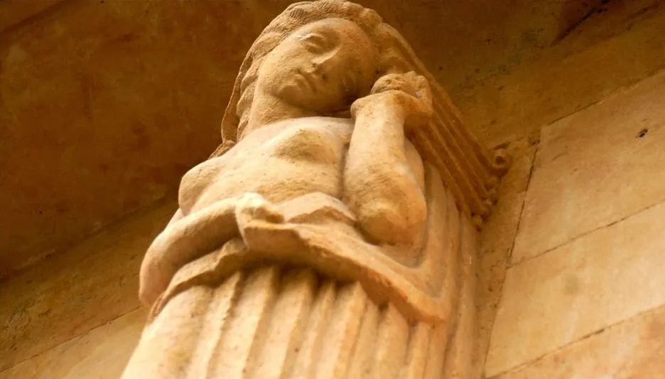 Clásica y delicada, la mujer que representa al Arte, se gira hacia el muro, mostrando un objeto