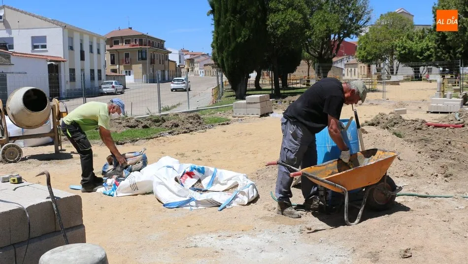 Empleados municipales proceden a la colocación del bordillo que delimita la nueva pista deportiva / CORRAL