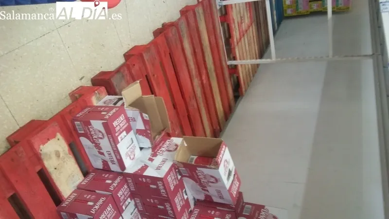 Cartel avisando de los problemas de suministro de algunos productos y estanterías vacías por la compra masiva y las dificultades para reponer rápidamente