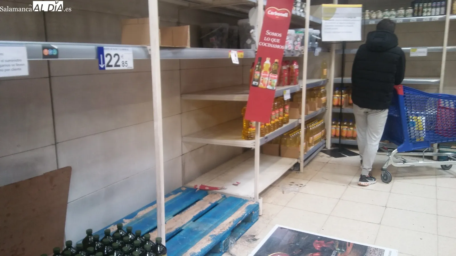 Cartel avisando de los problemas de suministro de algunos productos y estanterías vacías por la compra masiva y las dificultades para reponer rápidamente