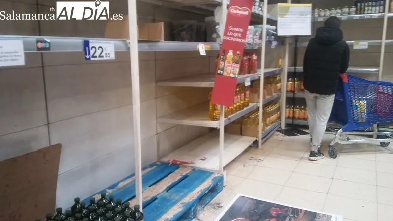 Cartel avisando de los problemas de suministro de algunos productos y estanterías vacías por la compra masiva y las dificultades para reponer rápidamente