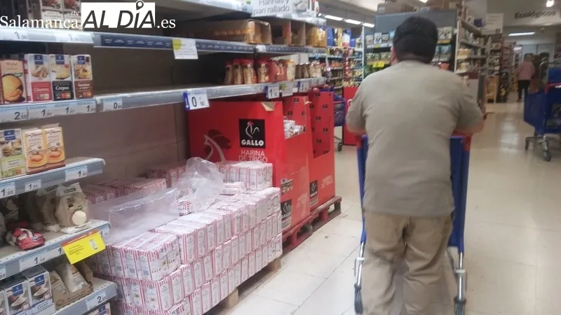 Cartel avisando de los problemas de suministro de algunos productos y estanterías vacías por la compra masiva y las dificultades para reponer rápidamente