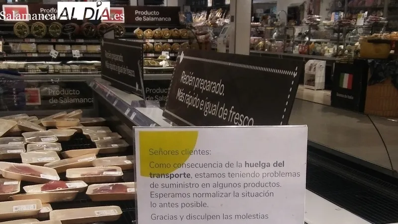 Cartel avisando de los problemas de suministro de algunos productos y estanterías vacías por la compra masiva y las dificultades para reponer rápidamente