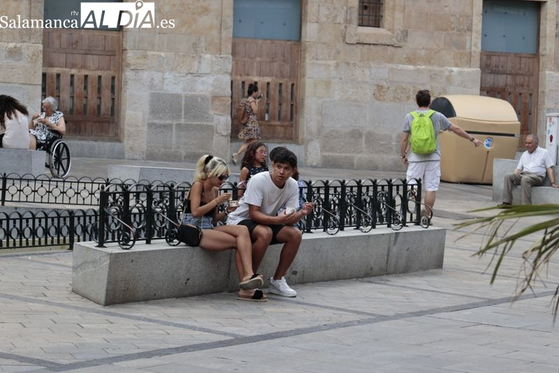 Varios jóvenes sentados en un banco en una céntrica calle de Salamanca. Foto de archivo