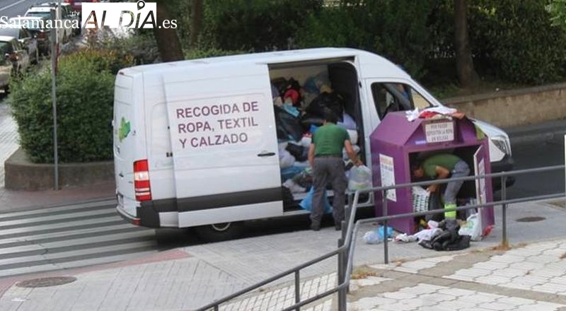 Trabajadores de la cooperativa Porsiete recogiendo ropa usada de uno de los contenedores morados de Salamanca. Foto de archivo