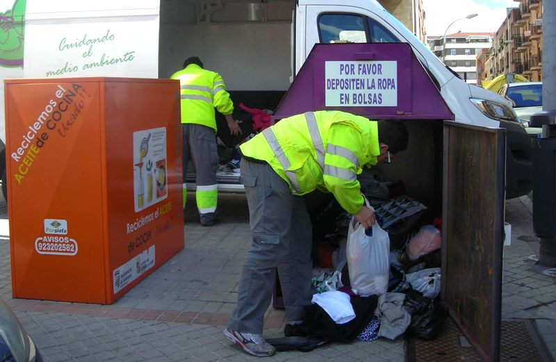 Trabajadores de la cooperativa Porsiete recogiendo ropa usada de uno de los contenedores morados de Salamanca. Foto Porsiete