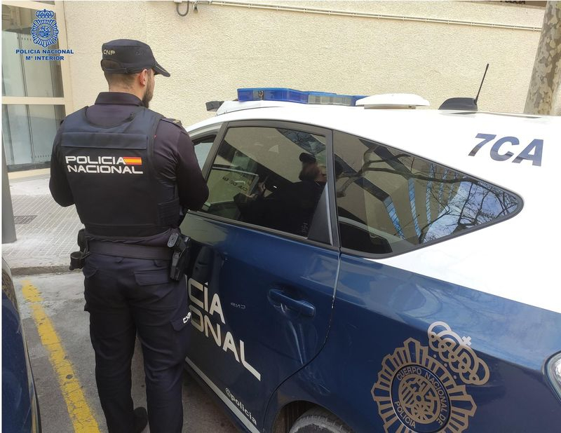 Agente de la Policía Nacional de espaldas, junto a un coche patrulla. Foto: EP.