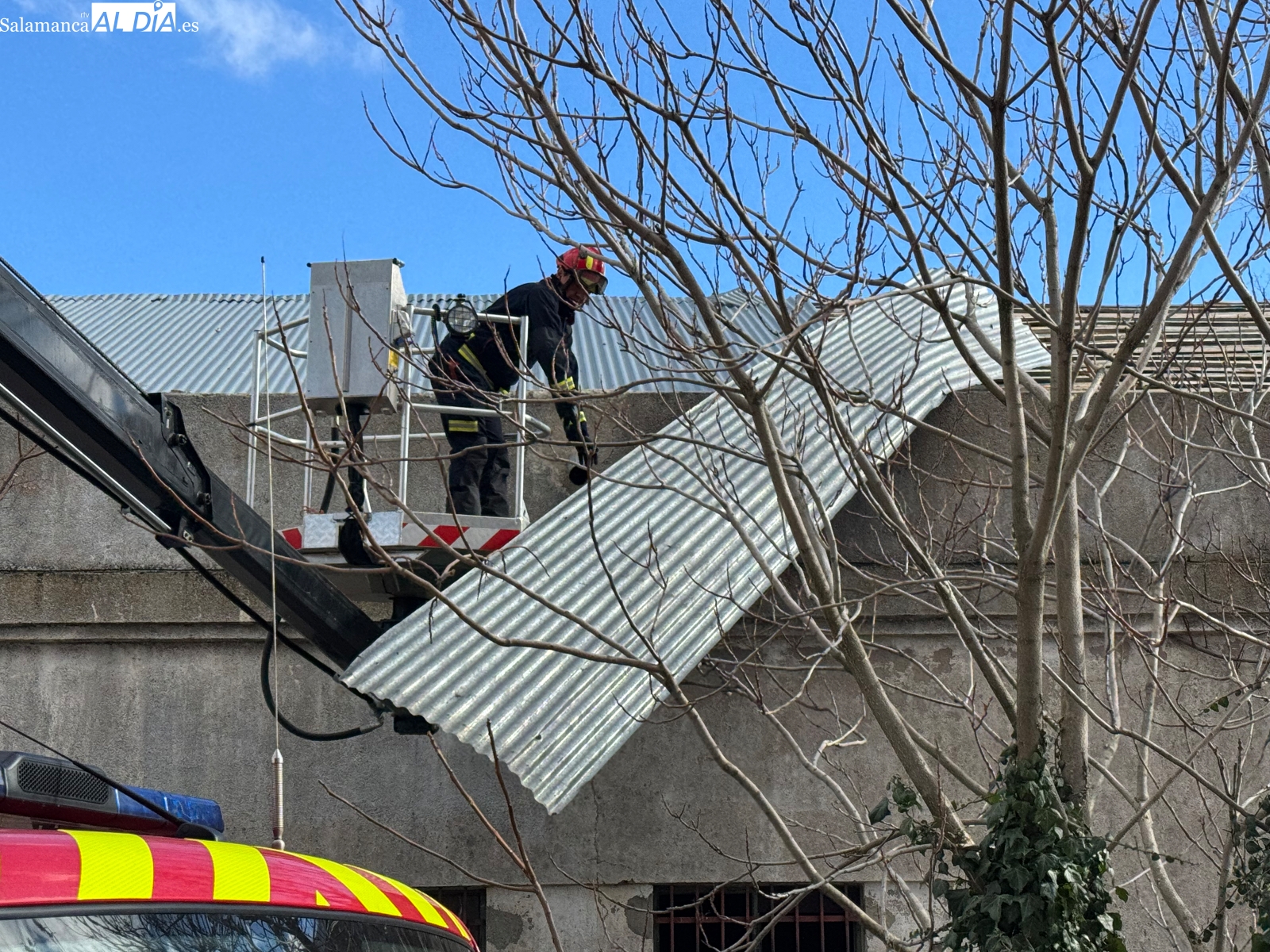 Efectivos voluntarios de los bomberos retiran una gran chapa metálica de la antigua fabrica de harinas para evitar su caída a la calle