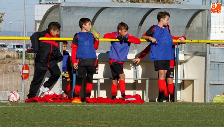 Unos niños observan a sus compañeros en un partido de fútbol base