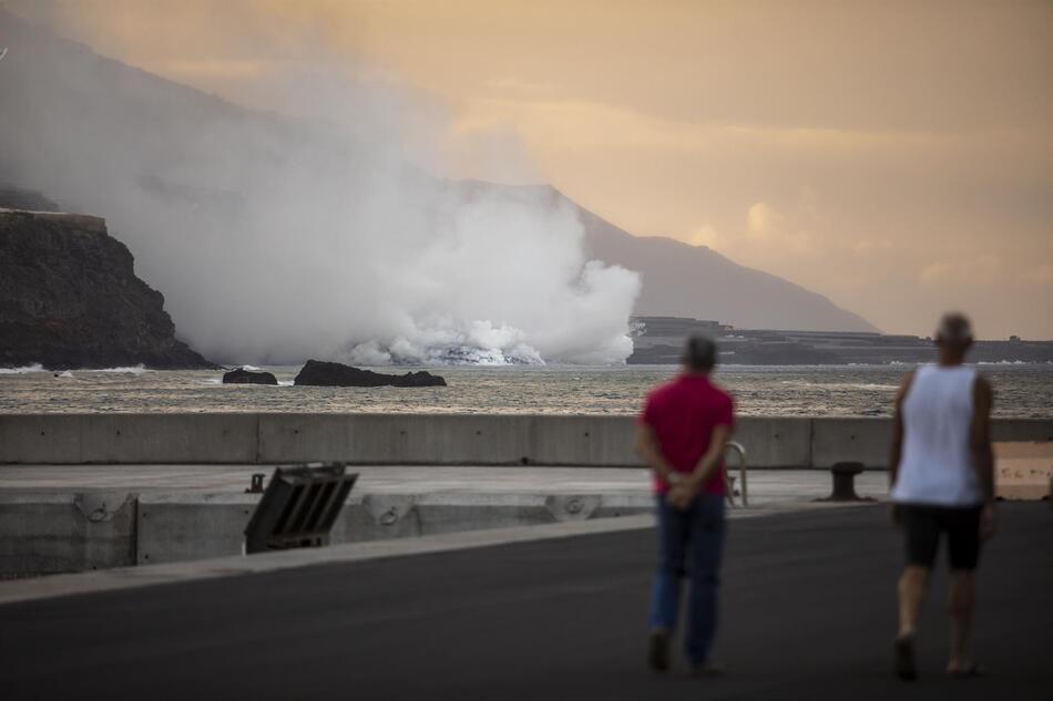 Dos personas observan la columna de humo y la lava del volcán de Cumbre Vieja a su llegada al Océano Atlántico. Foto: EP